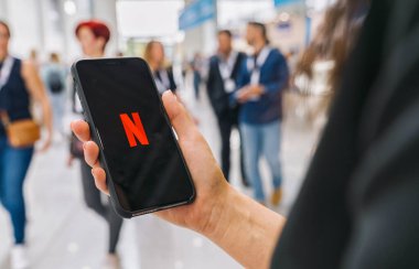BERLİN, ALMANY AĞUSTOS 2019: Netflix uygulamasının logosu olan iPhone X 'leri tutan kadın. Genç kadın film kütüphanesine göz atıyor. Ne izleyecekmiş?.