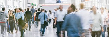 Ticaret fuarında yürüyen büyük bir iş adamı kalabalığı.