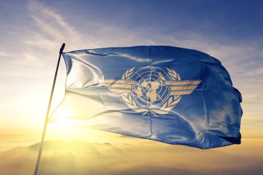Uluslararası Sivil Havacılık organizasyonu ICAO bayrak Tekstil Kumaş kumaş üst gündoğumu sis sis üzerinde sallayarak