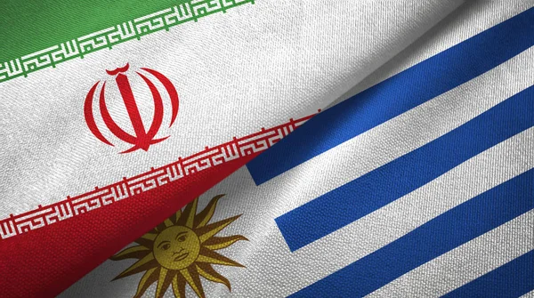 Иран и Уругвай два флага текстильная ткань, текстура ткани — стоковое фото