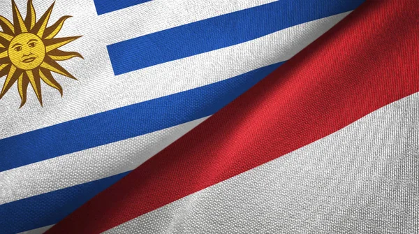 Uruguay e Indonesia dos banderas de tela textil, textura de tela —  Fotos de Stock