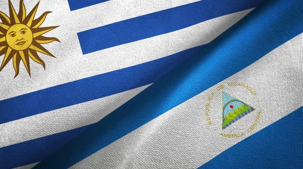 Уругвай и Никарагуа два флага текстильная ткань, текстура ткани — стоковое фото