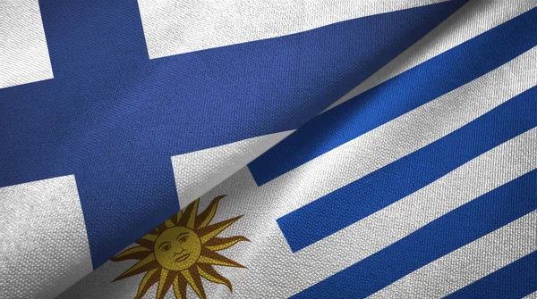 Finlândia e Uruguai duas bandeiras pano têxtil, textura de tecido — Fotografia de Stock