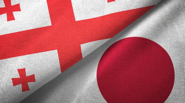 Gruzja i Japonia dwie flagi tkanina tekstylna, tekstura tkaniny — Zdjęcie stockowe