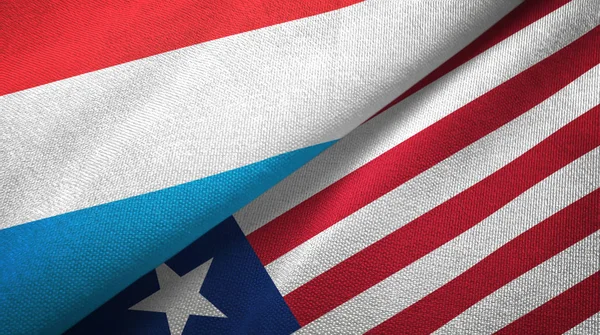 Luxemburg en Liberia twee vlaggen textiel doek, weefsel textuur — Stockfoto