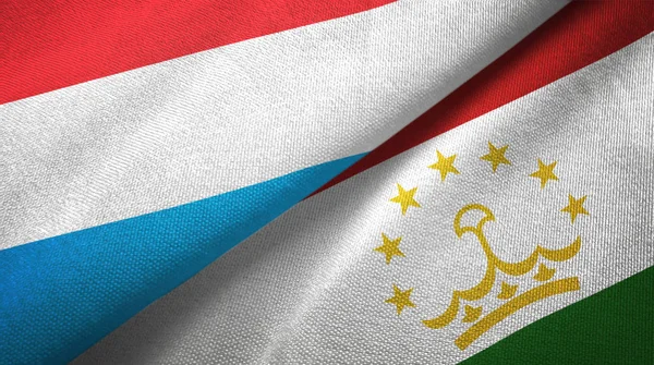 Люксембург и Таджикистан два флага текстильная ткань, текстура ткани — стоковое фото