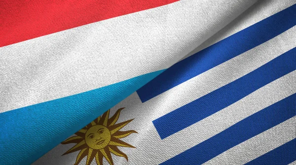 Luxemburgo e Uruguai duas bandeiras de pano têxtil, textura de tecido — Fotografia de Stock