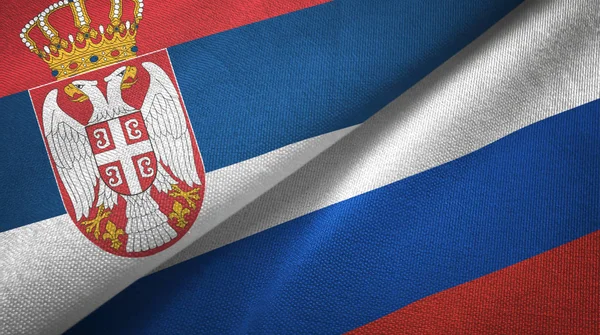 Serbia i Rosja dwie flagi tkanina tekstylna, tekstura tkaniny — Zdjęcie stockowe