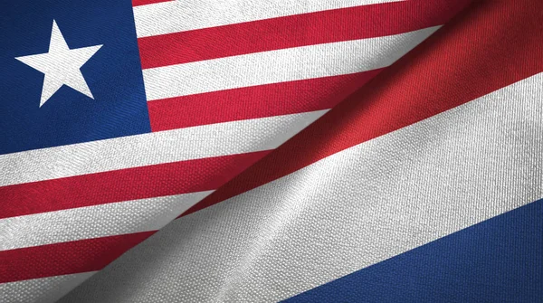 Либерия и Нидерланды два флага текстильная ткань, текстура ткани — стоковое фото