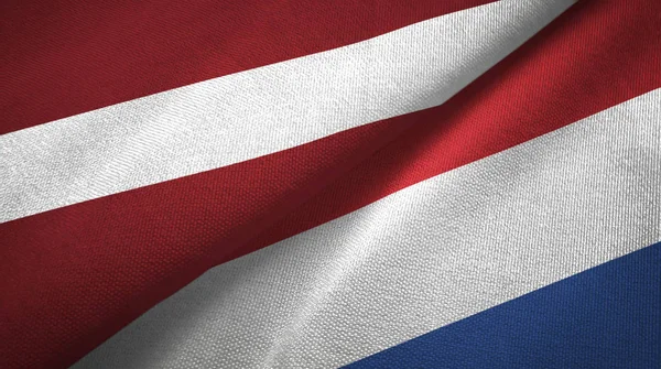 Letonia y Países Bajos dos banderas tela textil, textura de la tela —  Fotos de Stock