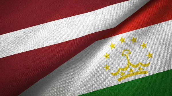 Латвия и Таджикистан два флага текстильная ткань, текстура ткани — стоковое фото