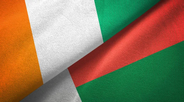 Cote Divoire och Madagaskar två flaggor textil tyg, tyg konsistens — Stockfoto