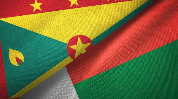 Grenada és Madagaszkár két zászló textil ruhával, szövet textúra — Stock Fotó