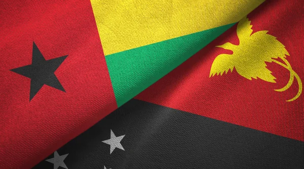 Guinee-Bissau en Papoea-Nieuw-Guinea twee vlaggen textiel doek, stof textuur — Stockfoto