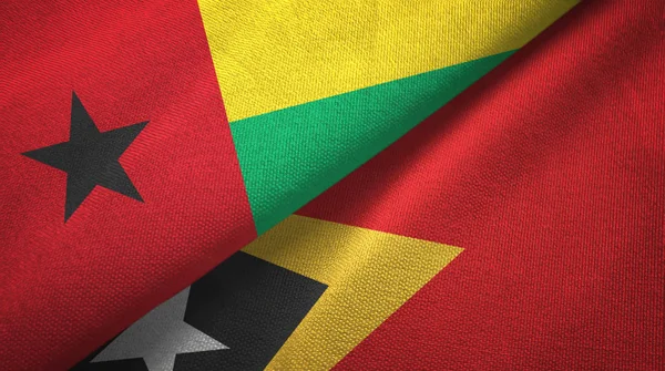 Guinee-Bissau en Timor-leste Oost-Timor twee vlaggen textiel doek, weefsel textuur — Stockfoto