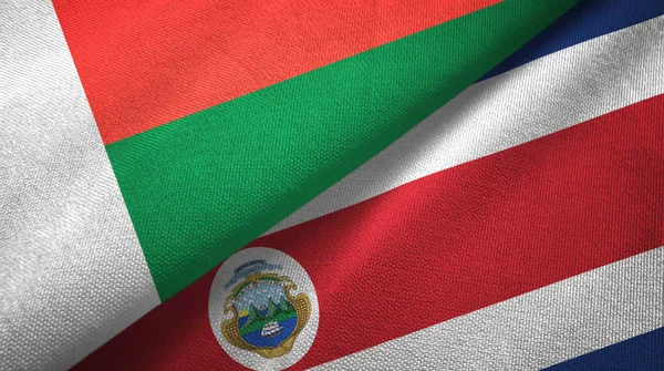 Madagascar et Costa Rica deux drapeaux tissu textile, texture du tissu — Photo
