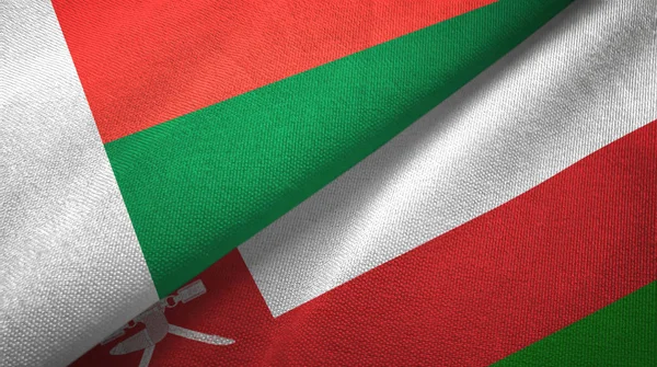 Madagaskar i Oman dwie flagi tkanina tekstylna, tekstura tkaniny — Zdjęcie stockowe