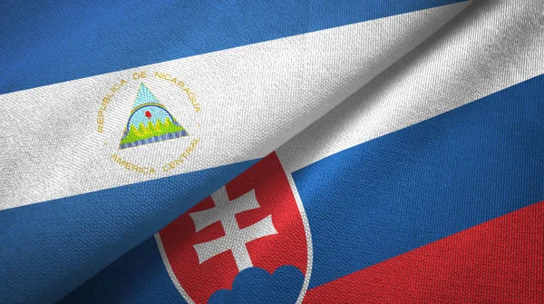 Nicaragua et Slovaquie deux drapeaux tissu textile, texture du tissu — Photo