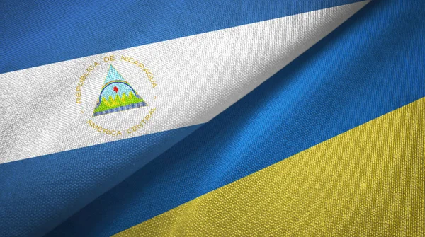 Nicaragua and Ukraine two flags textile cloth, fabric texture — Stock Photo, Image