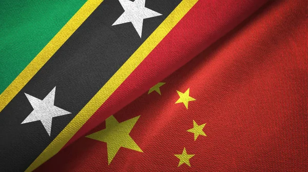 São Cristóvão e Nevis e China duas bandeiras de pano têxtil, textura de tecido — Fotografia de Stock