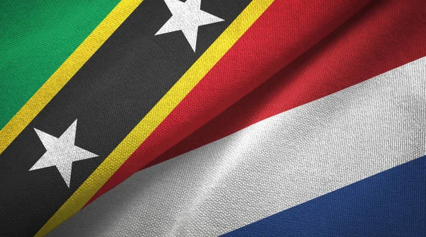 Saint Kitts i Nevis i Holandii dwie flagi tkanina tekstylna, tekstura tkaniny — Zdjęcie stockowe