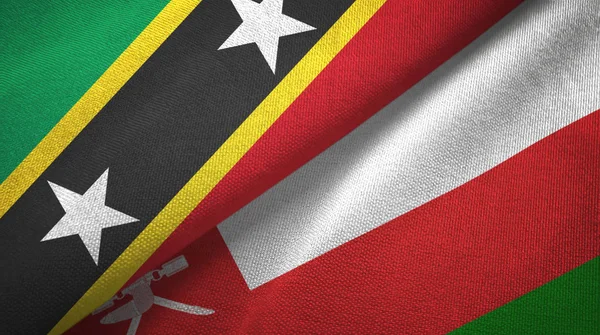 São Cristóvão e Nevis e Omã duas bandeiras de pano têxtil, textura de tecido — Fotografia de Stock