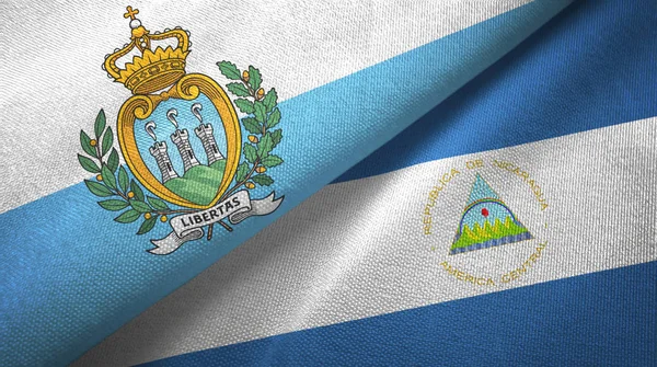 San Marino e Nicarágua duas bandeiras de pano têxtil, textura de tecido — Fotografia de Stock
