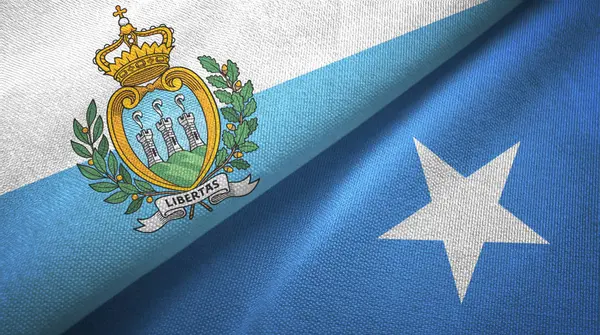 San Marino e Somália duas bandeiras pano têxtil, textura de tecido — Fotografia de Stock