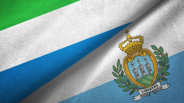 Serra Leoa e San Marino duas bandeiras de pano têxtil, textura de tecido — Fotografia de Stock