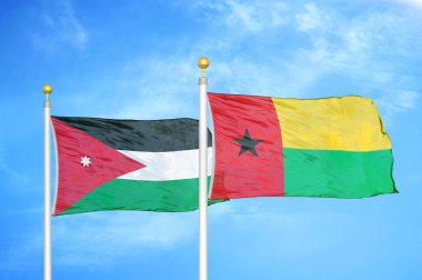 Ürdün ve Gine-Bissau bayrak direğinde iki bayrak ve mavi bulutlu arka plan