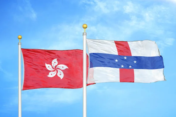 Hong Kong and Netherlands Antilles two flags on flagpoles and blue cloudy sky background