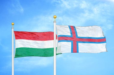 Macaristan ve Faroe Adaları bayrak direkleri ve mavi bulutlu arka planda iki bayrak