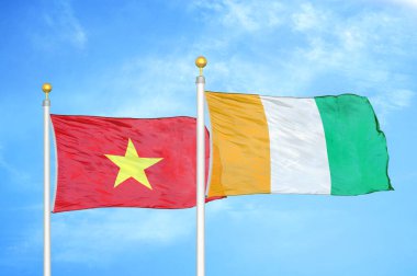 Vietnam ve Fildişi Fildişi Sahilleri bayrak direkleri ve mavi bulutlu arka planda iki bayrak
