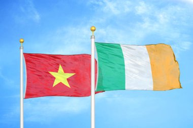 Vietnam ve İrlanda bayrak direkleri üzerinde iki bayrak ve mavi bulutlu arka plan