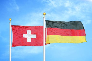 İsviçre ve Almanya bayrak direkleri ve mavi bulutlu arka planda iki bayrak