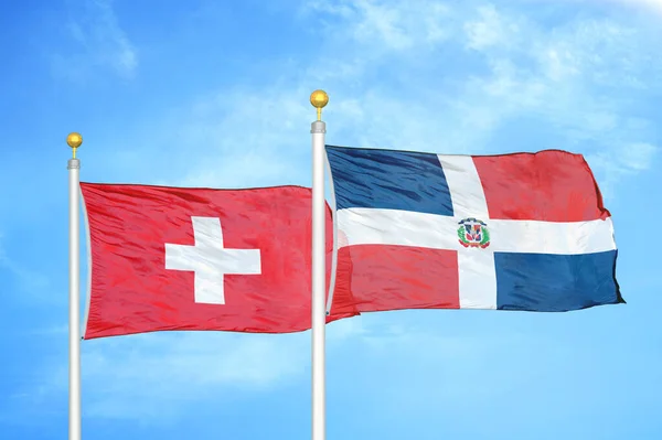スイスとドミニカ共和国の旗竿と青空の背景に2つの旗 — ストック写真