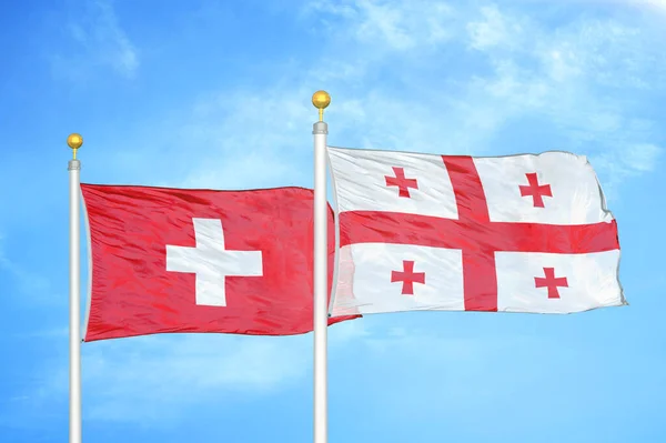 Zwitserland Georgië Twee Vlaggen Vlaggenmasten Blauwe Bewolkte Hemelachtergrond — Stockfoto