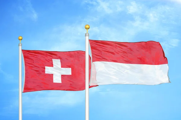 スイスとインドネシアの旗竿と青空の背景に2つの旗 — ストック写真