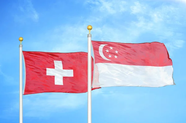 旗竿にスイスとシンガポールの2つの旗と青空の背景 — ストック写真
