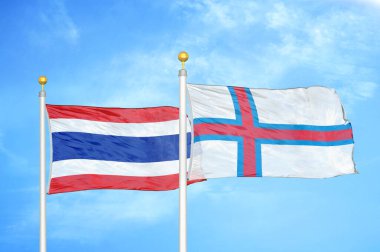 Tayland ve Faroe Adaları bayrak direkleri ve mavi bulutlu arka planda iki bayrak