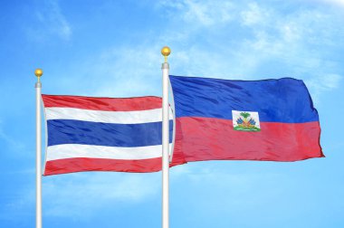 Tayland ve Haiti bayrak direkleri ve mavi bulutlu arka planda iki bayrak