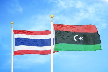 Tayland ve Libya bayrak direkleri ve mavi bulutlu arka planda iki bayrak
