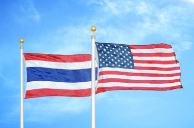 Tayland ve ABD bayrak direkleri ve mavi bulutlu arka planda iki bayrak
