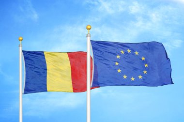 Romanya ve Avrupa Birliği bayrak direkleri ve mavi bulutlu arka plan üzerinde iki bayrak