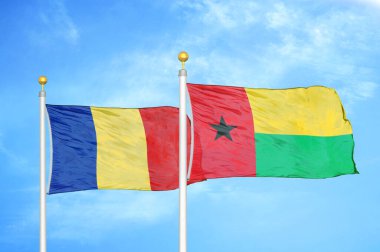 Romanya ve Gine-Bissau bayrak direkleri ve mavi bulutlu arka planda iki bayrak