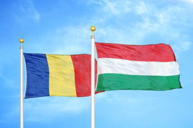 Romanya ve Macaristan bayrak direkleri ve mavi bulutlu arka planda iki bayrak
