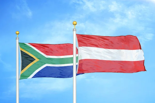 南アフリカとオーストリアの旗竿と青空の背景に2つの旗 — ストック写真