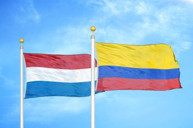 Hollanda ve Kolombiya bayrak direkleri ve mavi bulutlu arka planda iki bayrak