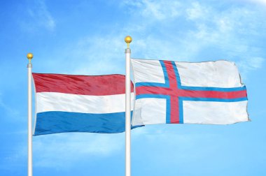 Hollanda ve Faroe Adaları bayrak direkleri ve mavi bulutlu arka planda iki bayrak