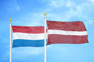 Hollanda ve Letonya bayrak direkleri ve mavi bulutlu arka planda iki bayrak